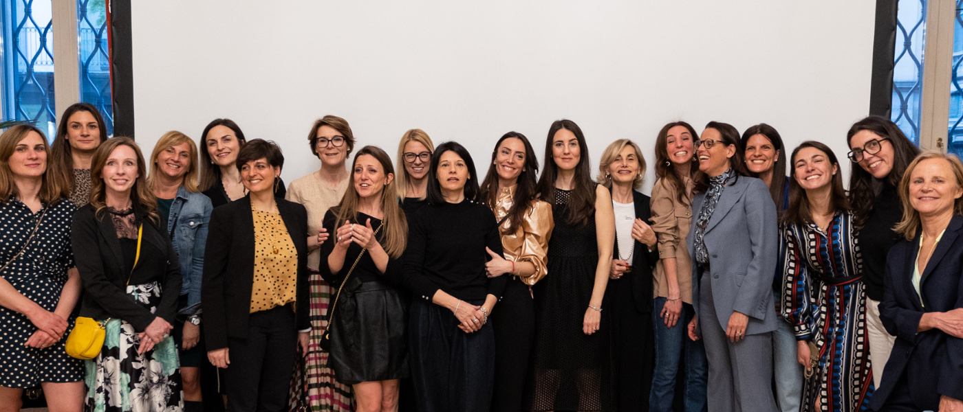 Group of professional women standing together and smiling for a group photo at an event.