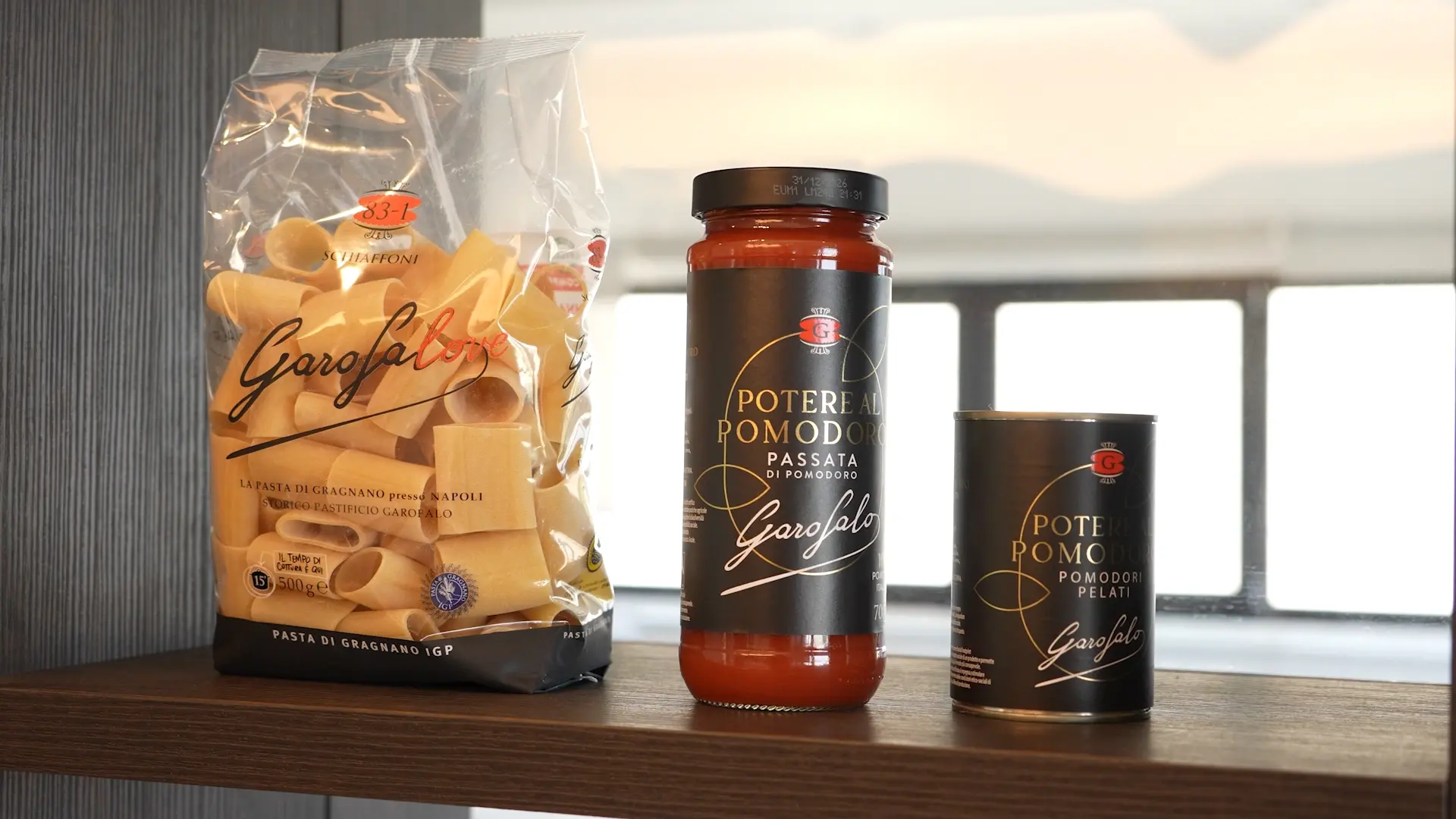 Bag of Garofalo pasta on a wooden shelf next to two jars of tomato sauce labeled Potere di Pomodoro Garofalo
