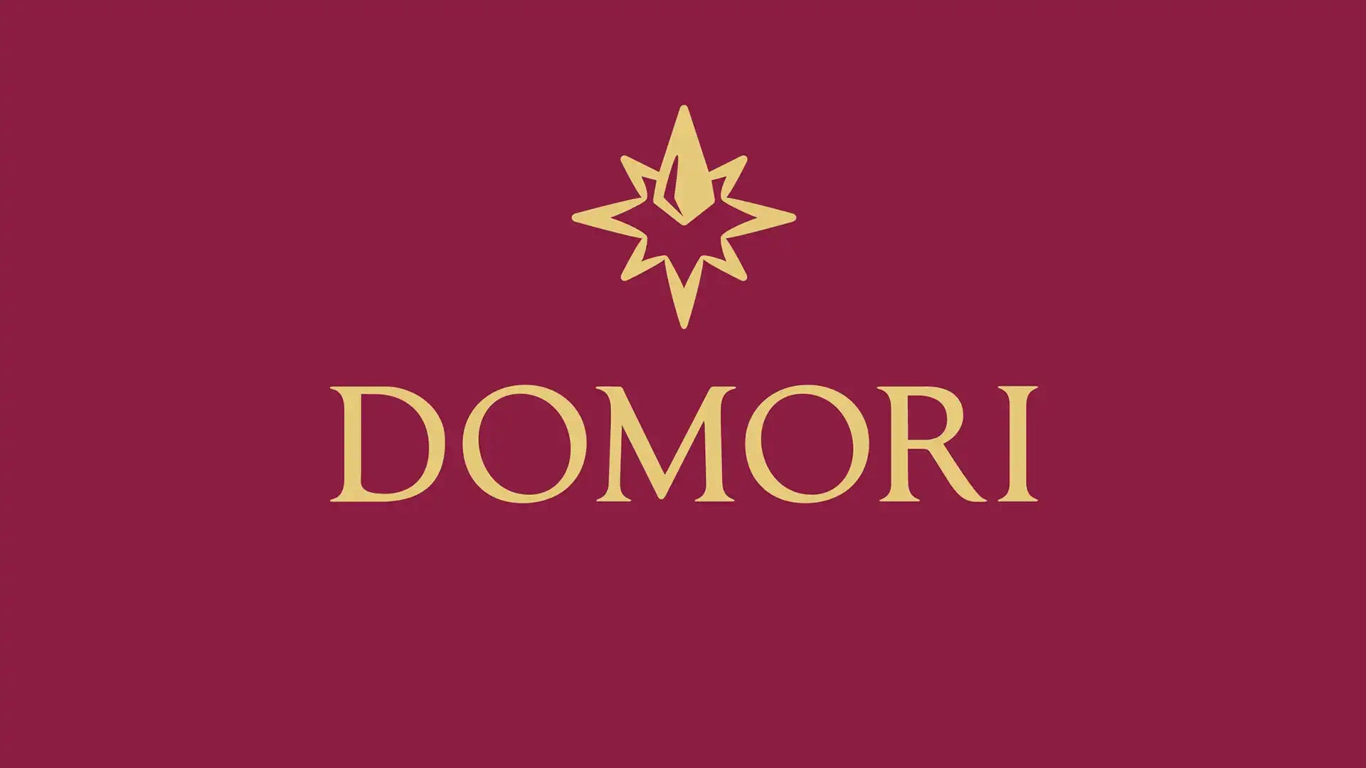 Domori brand logo: gold star-like emblem above the word DOMORI on a burgundy background.