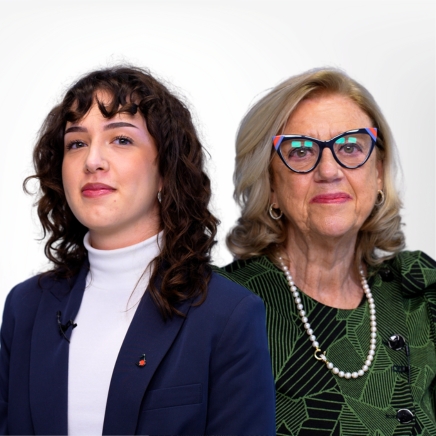 Two women posing side by side: a young woman with dark curly hair in a white turtleneck and navy blazer, and an older woman with blonde hair, colorful glasses, a green patterned blouse, and a pearl necklace.