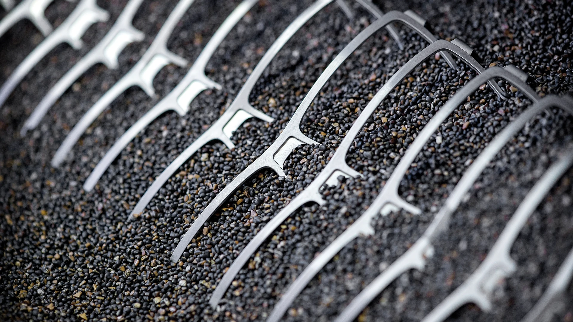 Close-up of a metal grate or grid laid over a bed of small dark stones.