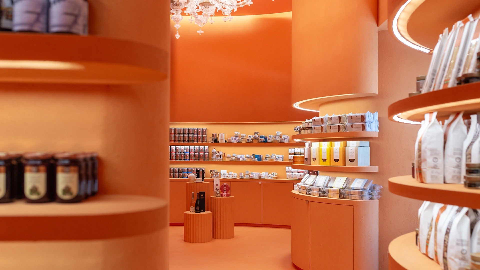 Orange-toned store interior with circular shelves holding tea, jars, and packaged goods.
