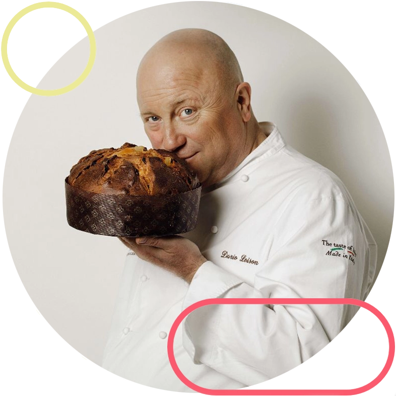 Chef in a white uniform holds and smells a tall panettone loaf.