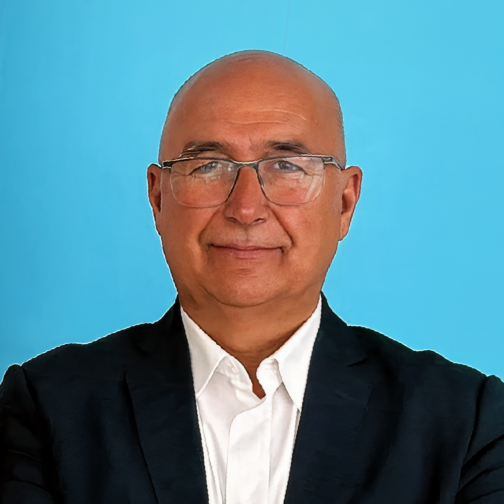 Portrait of a smiling, bald man wearing glasses and a dark suit against a bright blue background