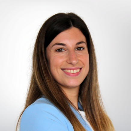 Smiling woman with long brown hair wearing a light blue blouse, facing slightly to the left.