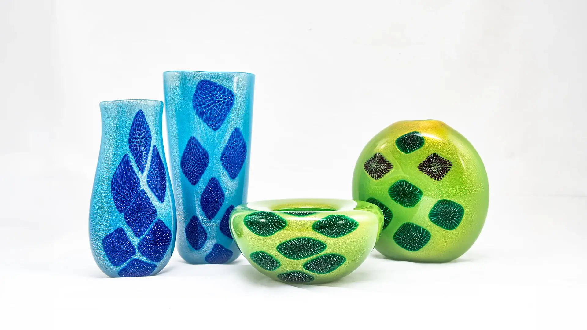Blue glass vases and green patterned bowls on a white background.