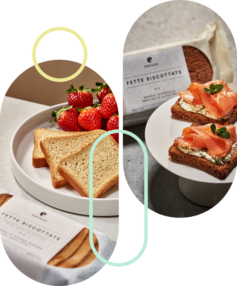 Toast with strawberries on a plate beside packaging of fette biscottate, plus salmon crostini on a separate plate in the background.