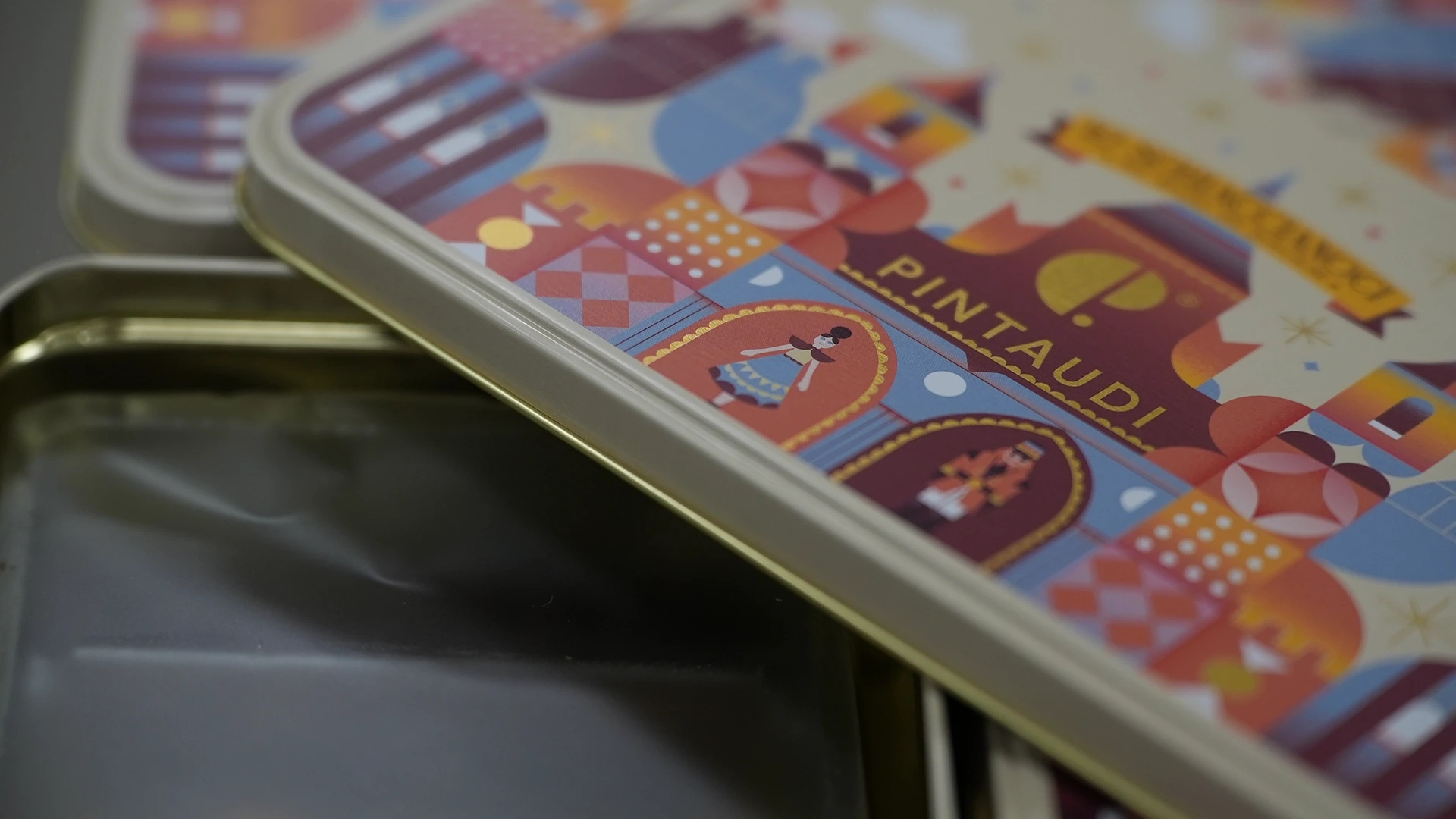 Close-up of stacked colorful decorative tin boxes with geometric patterns and curved metal edges.