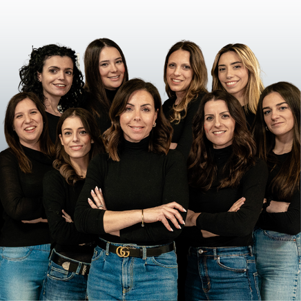 Group photo of nine women in black tops and jeans, standing close together with arms crossed, smiling at the camera.