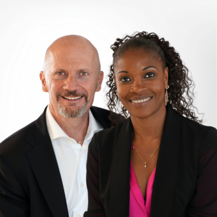Two smiling professionals in business attire posing together against a white background.